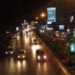 Cars driving down a busy road by night