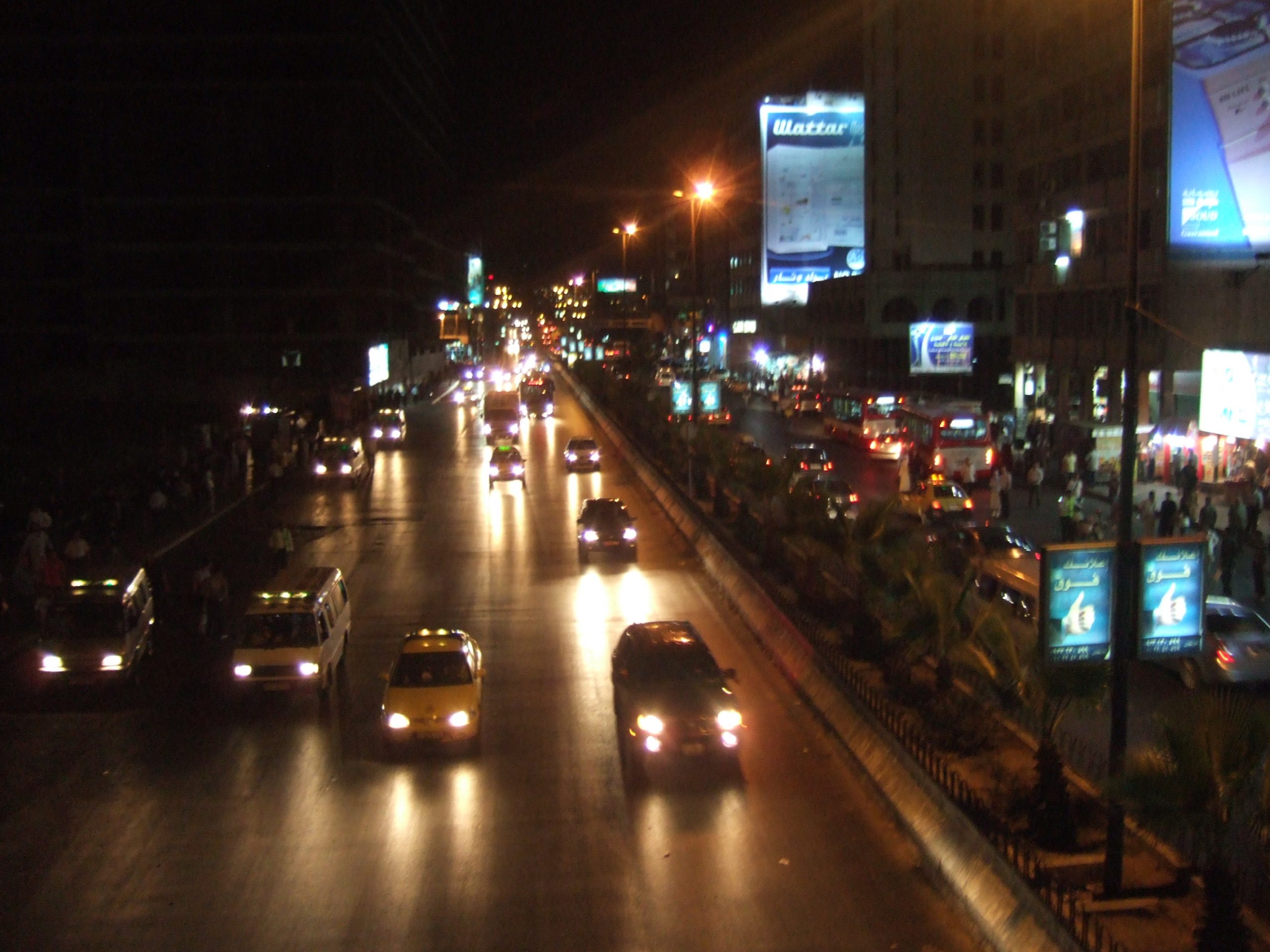 Cars driving down a busy road by night