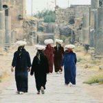 People walking down a ruined colonnade