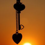 Heart and key silhouetted against sunset