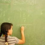 Girl writing sums on blackboard