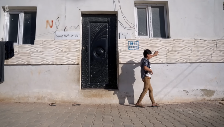 Child tracing his hand across one of the homes in Al Nouri refugee camp. © ARTE.